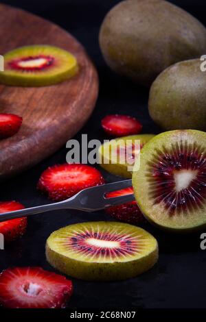 Close view of tiny fruits, green and red kiwis, and a red ripe strawberry. Stock Photo