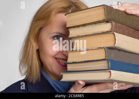 plus size caucasian business office woman. isolated in white. looks out from behind a stack of books. The concept of adult learning Stock Photo