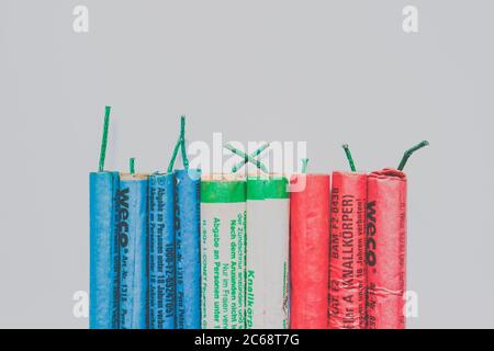 Firecrackers ('Böller') of different types (pirate type, retro) in blue, white and red with German text about age restrictions on a pale white background. Stock Photo