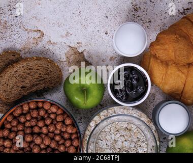 A perfect breakfast table full of fresh fruits: apple and orange, different bread types: croissants and toasted bread, jam, salty sticks, oats and kid Stock Photo