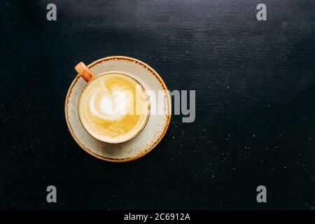 Coffee with milk in a cup. Cappuccino. On a black wood background. Top view. Free copy space. Stock Photo