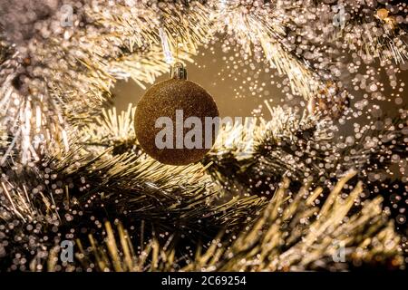 Christmas ball in christmas tree with water bokeh. Beautiful back light. Element of decoration. Greeting card. Stock Photo