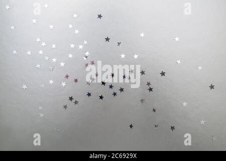 silver stars on a silver background. Christmas and New Year background of silver confetti stars. Stock Photo