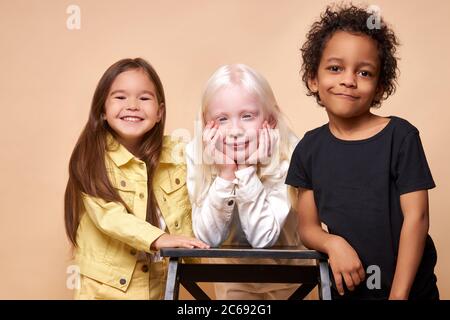 portrait of beautiful kids with natural unusual appearance. girl with albinism syndrome is friends with black african boy and american girl. children Stock Photo