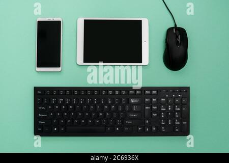 Cyber Monday flat lay on turquoise background. Keyboard, tablet, phone and computer mouse composition. Copy space. Stock Photo