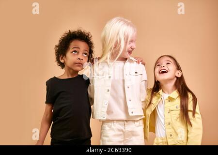portrait of cheerful positive kids, multiethnic children isolated in studio. adorable afro boy and albino, caucasian girls stand together, posing. int Stock Photo