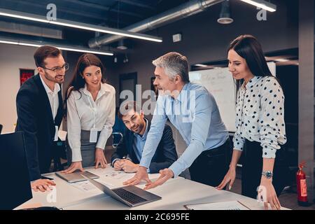 Five young modern people in formalwear working together while standing indoor Stock Photo