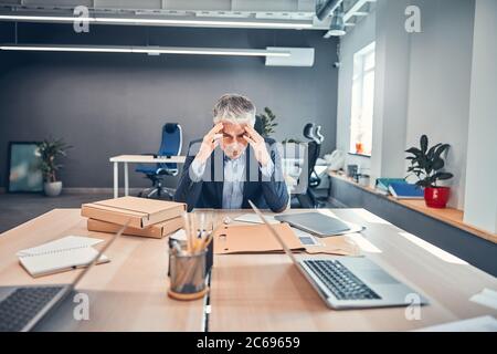 Man at the desk feeling headache and holding two hand Stock Photo