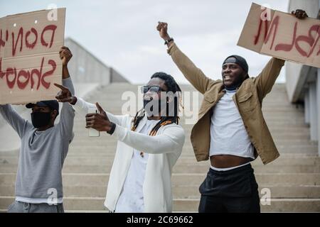 solidarity rally for black african american people in USA. three black guys protest against injustice, they go on demonstrations