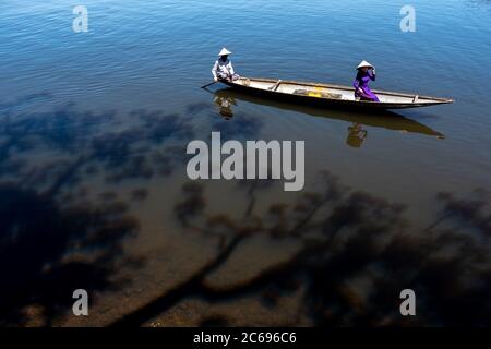 Two women in traditional clothing sitting in a boat, Vietnam Stock Photo