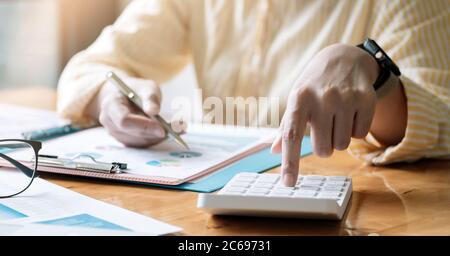 Accountant or bookkeeper working on desk using calculator, accounting finance concept.