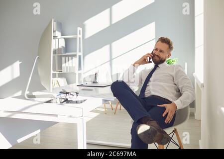 Confident adult businessman having phone conversation in office Stock Photo
