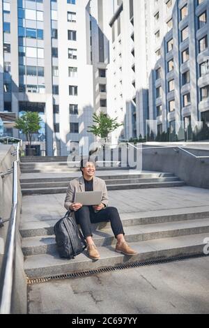 Joyful young man using notebook on the street Stock Photo