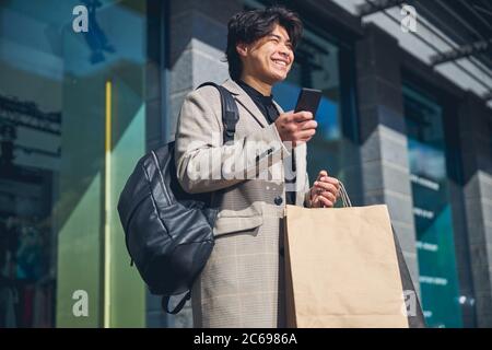 Joyful young man using smartphone on the street Stock Photo