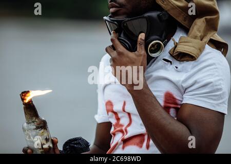 portrait of young african american black man in gas mask in the streets, guy is wearing t-shirt with BLM inscription. black lives matter concept Stock Photo