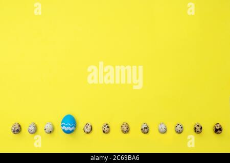 Row from quail and one easter eggs over yellow background. Place for text. Easter hipster concept. Eggs as symbol months. Stock Photo
