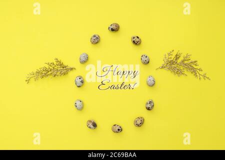 Quail eggs laid in the shape of an egg with golden wings like chicken on yellow background. Organic food. Happy easter lettering. Stock Photo