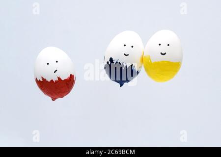 Flying three easter white eggs in paint on light background. Minimal hipster concept. Faces on eggs. Stock Photo