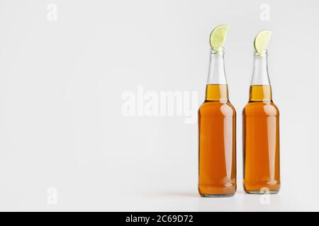 Two bottles of light ale with pieces of lime on a white background Stock Photo