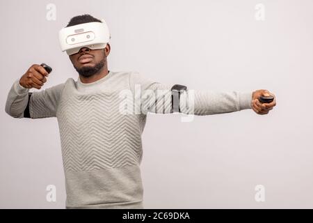 Stylishly dressed african guy using new VR technology headset, learning material and getting knowledge and practice through 3D video glasses. Virtual Stock Photo
