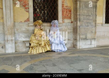 Venice, Italy - March 7, 2011: Two unidentified masked persons in gold and white costumes on St. Mark's Square during the Carnival of Venice. The 2011 Stock Photo