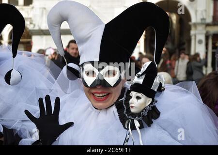 Venice, Italy - Mar 7, 2011: Unidentified masked person in Arlecchino costume among crowd in St. Mark's Square during the Carnival. The 2011 carnival Stock Photo