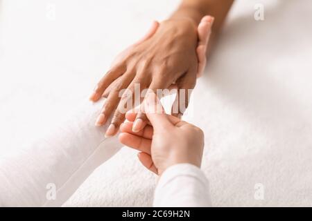 Top view of therapist rubbing black woman fingers Stock Photo