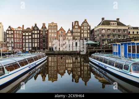 AMSTERDAM, NETHERLANDS - 16TH FEBRUARY 2016: Old Buildings along the Damrak in Amsterdam during the day. Boats can be seen. Stock Photo