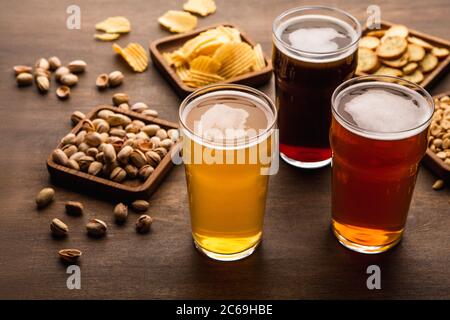 Table for company of friends. Crispy snacks and different types of beer in glasses Stock Photo