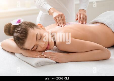 Beautiful lady getting salt massage at modern spa Stock Photo
