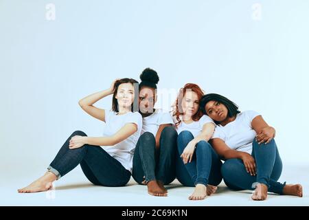 friendship, fashion, body positive, diverse female beauty concept - group of happy multicultural different size women in casual wear posing on white b Stock Photo