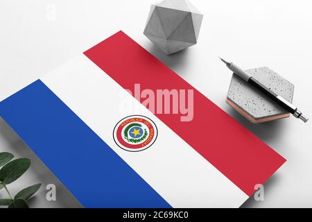 Paraguay flag on minimalist paper background. National invitation letter with stylish pen on stone. Communication concept. Stock Photo