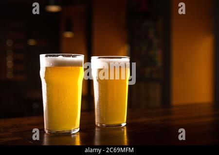 Order beer at pub. Glasses of ale on table in interior of dark pub Stock Photo