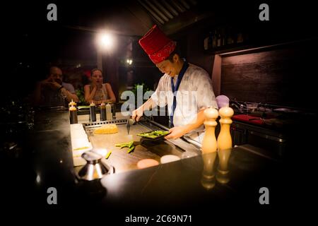 May, 2018 - Ari Atoll, Maldives: Happy teppanyaki chef cooking vegetables teppan in Japanese steakhouse on Mishi Sushi. Gourmet food luxury restaurant Stock Photo