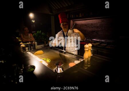 May, 2018 - Ari Atoll, Maldives: Happy teppanyaki chef cooking vegetables teppan in Japanese steakhouse on Mishi Sushi. Gourmet food luxury restaurant Stock Photo