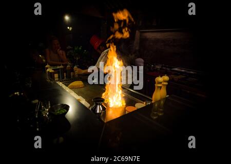 May, 2018 - Ari Atoll, Maldives: Happy teppanyaki chef cooking vegetables teppan in Japanese steakhouse on Mishi Sushi. Gourmet food luxury restaurant Stock Photo