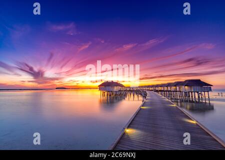 Amazing sunset sky and reflection on calm sea, Maldives beach landscape of luxury over water bungalows. Exotic scenery of summer vacation and holiday Stock Photo