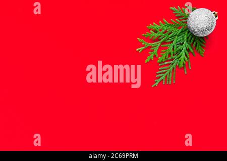 Christmas minimal composition. Christmas silver ball and fir tree branch on red background. Flat lay, top view. Copy space Stock Photo