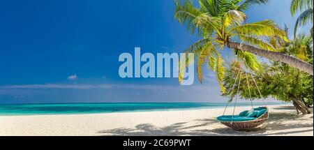Tropical beach panorama as summer landscape with beach swing or hammock and white sand and calm sea for beach banner. Perfect beach scene vacation