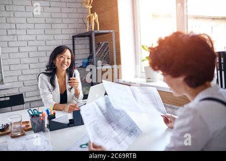 Business for people, cooperation between two sides, asian and caucasian deal. Two business ladies with papers Stock Photo