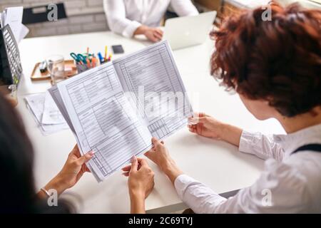 Busy people holding papers with work instruction, sitting on table, workteam in office. cooperation Stock Photo