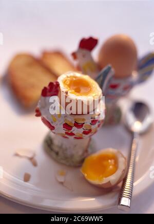 Soft boiled eggs for breakfast in chicken shaped egg cups Stock Photo