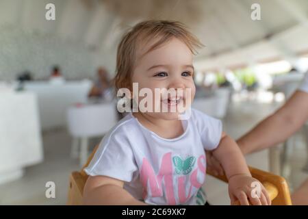 Adorable toddler girl eating healthy vegetables and unhealthy french fries potatoes. Cute happy baby child taking food from dish at daycare or nursery Stock Photo