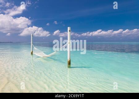 Tropical chill out, luxury beach with over water hammock endless sea view, exotic seascape. Summer vacation, holiday destination, relax and peaceful Stock Photo