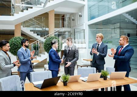 Ending of conversation in business center. Young leaders representatives of different countries shaking hands to each other Stock Photo