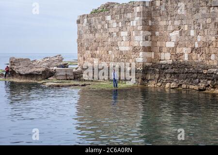 Angler next to ruins of ancient port in Byblos, largest city in the Mount Lebanon Governorate of Lebanon Stock Photo