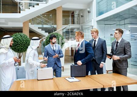 Translator between businessmen, sheikh and caucasian. Sheikh holding white case, caucasian black case. Translator of arabic and english languages Stock Photo