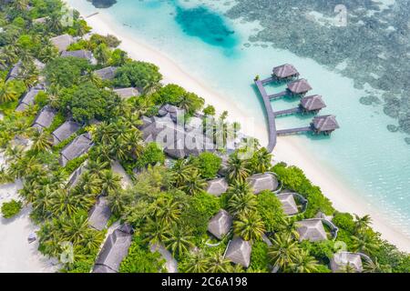 Perfect aerial landscape, luxury tropical resort or hotel with water villas and beautiful beach scenery. Amazing bird eyes view in Maldives, landscape