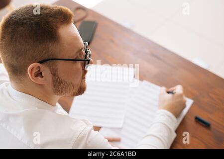 Back view of thoughtful musician wearing stylish eyeglasses thinking over musical notes Stock Photo