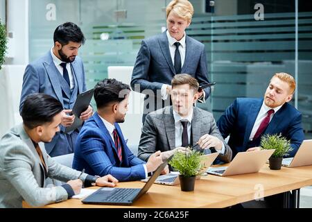 International meeting of young negotiators gathered to discuss new project using laptops. Green, plantations office background Stock Photo